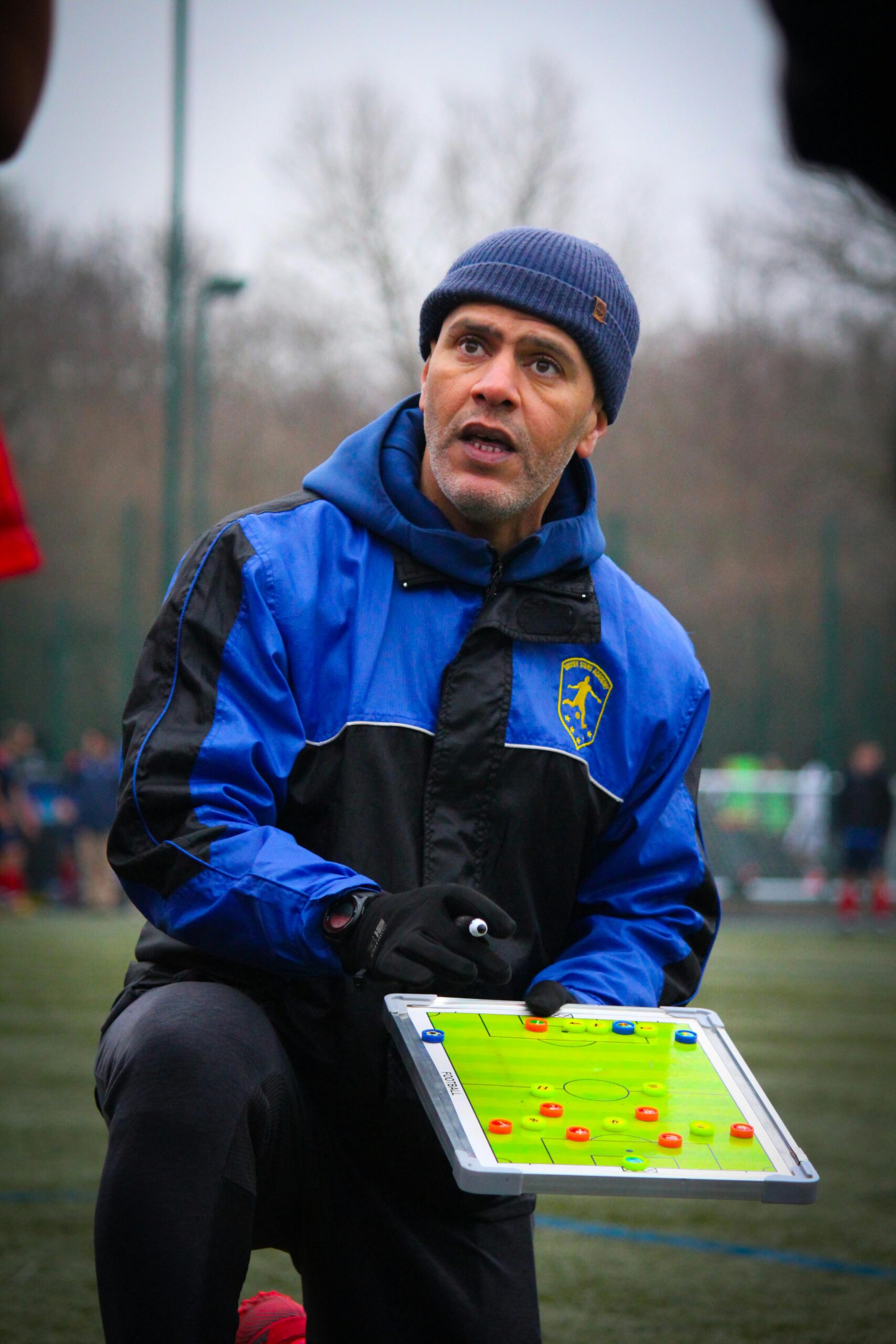 Soccer coach explaining strategy on field during training session.